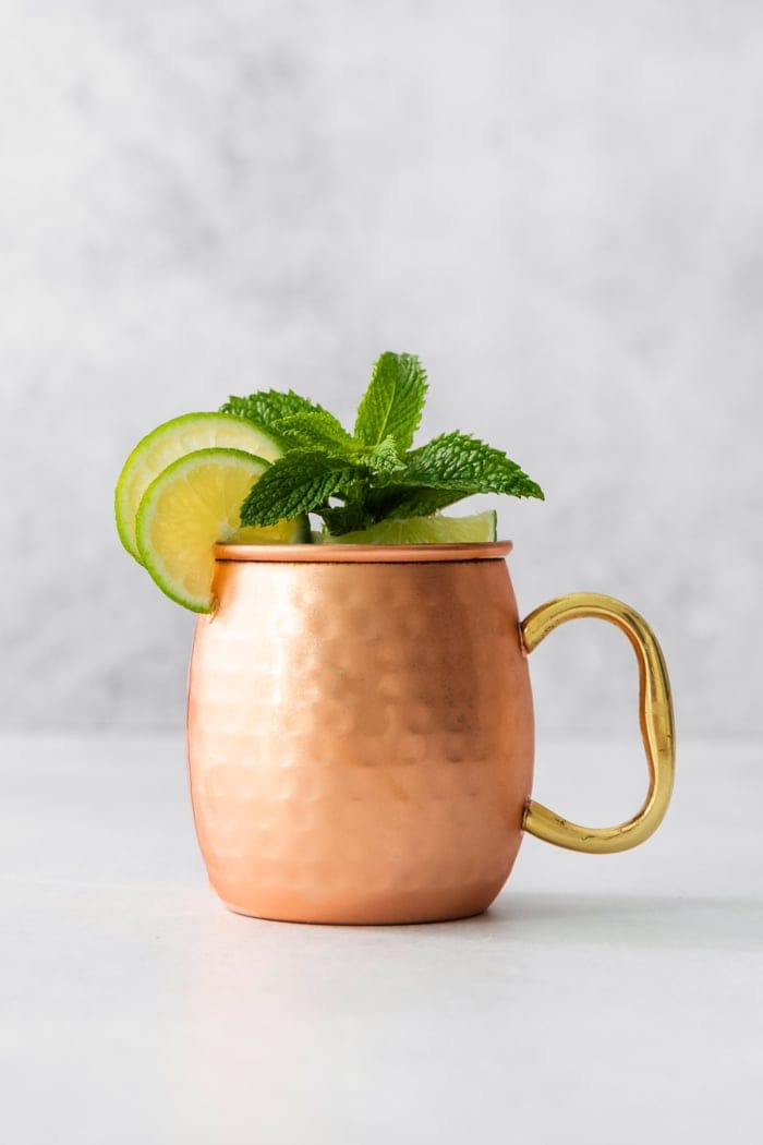 Copper mug with Moscow mule mocktail garnished with sprig of mint and lime