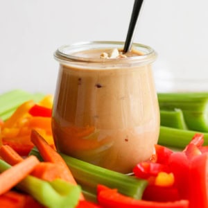 fresh cut vegetables with a jar of peanut sauce