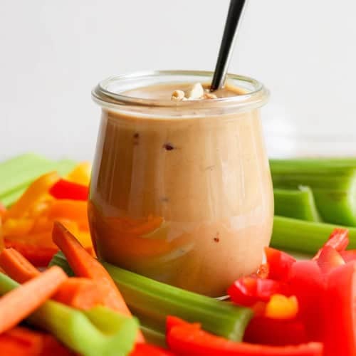 fresh cut vegetables with a jar of peanut sauce