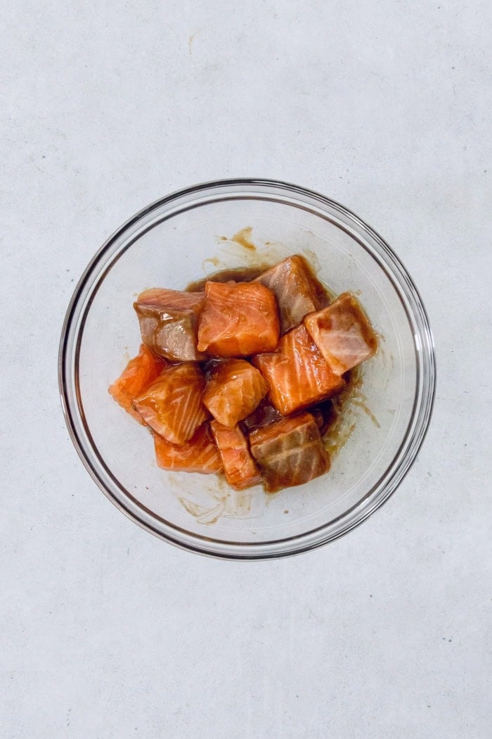Overhead view of raw salmon with oil and teriyaki sauce in bowl