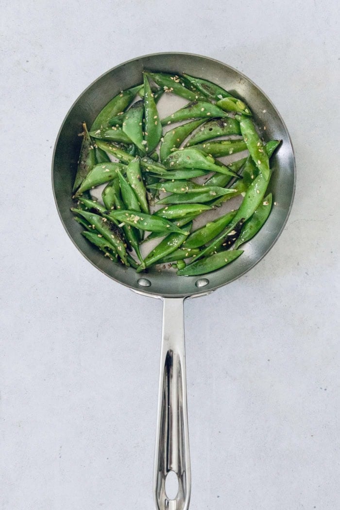 Overhead view of snap peas cooking in skillet