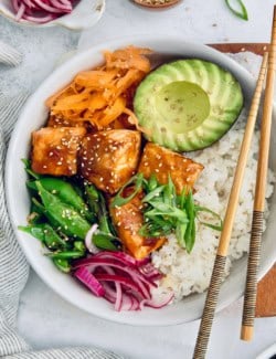 Overhead view of teriyaki salmon bowl with avocado, carrots, snap peas, and rice