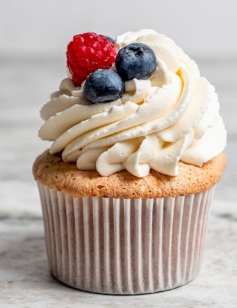 an angel food cupcake topped with white frosting and fresh berries