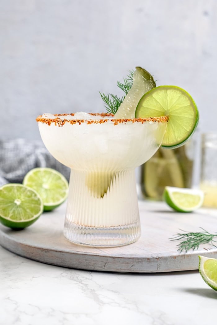 Pickle margarita garnished with pickle spear, dill, and lime wheel