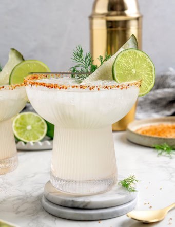 Pickle margarita garnished with pickle spear, dill, and lime wheel