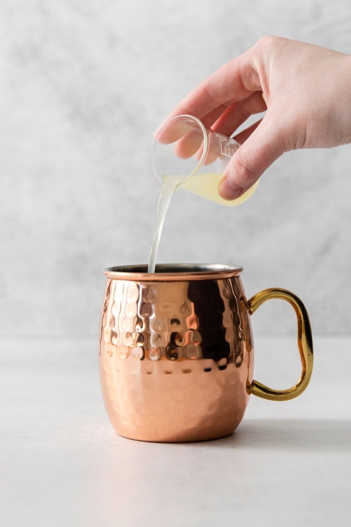 Pouring fresh lime juice into copper mug for Moscow mule