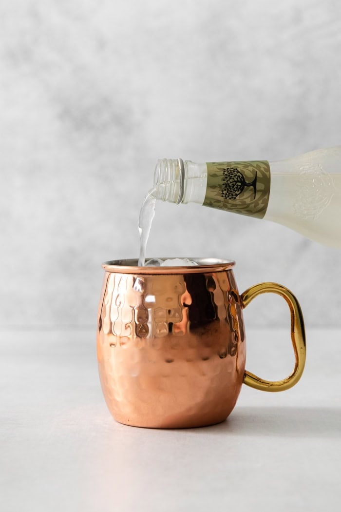 Pouring ginger beer into copper mug for Moscow mule