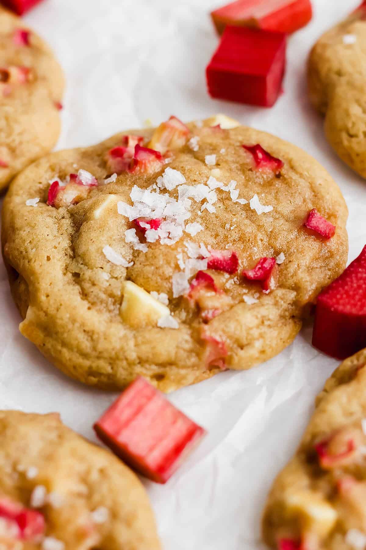 These easy Rhubarb Cookies are buttery, chewy, and a must-make for rhubarb season. White chocolate and flaky salt make them truly special! Closeup of rhubarb cookie topped with Maldon sea salt