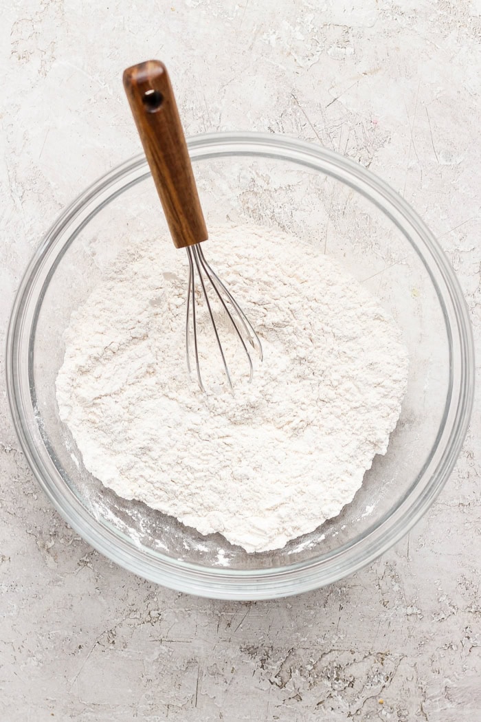 Overhead view of dry ingredients in glass mixing bowl with whisk
