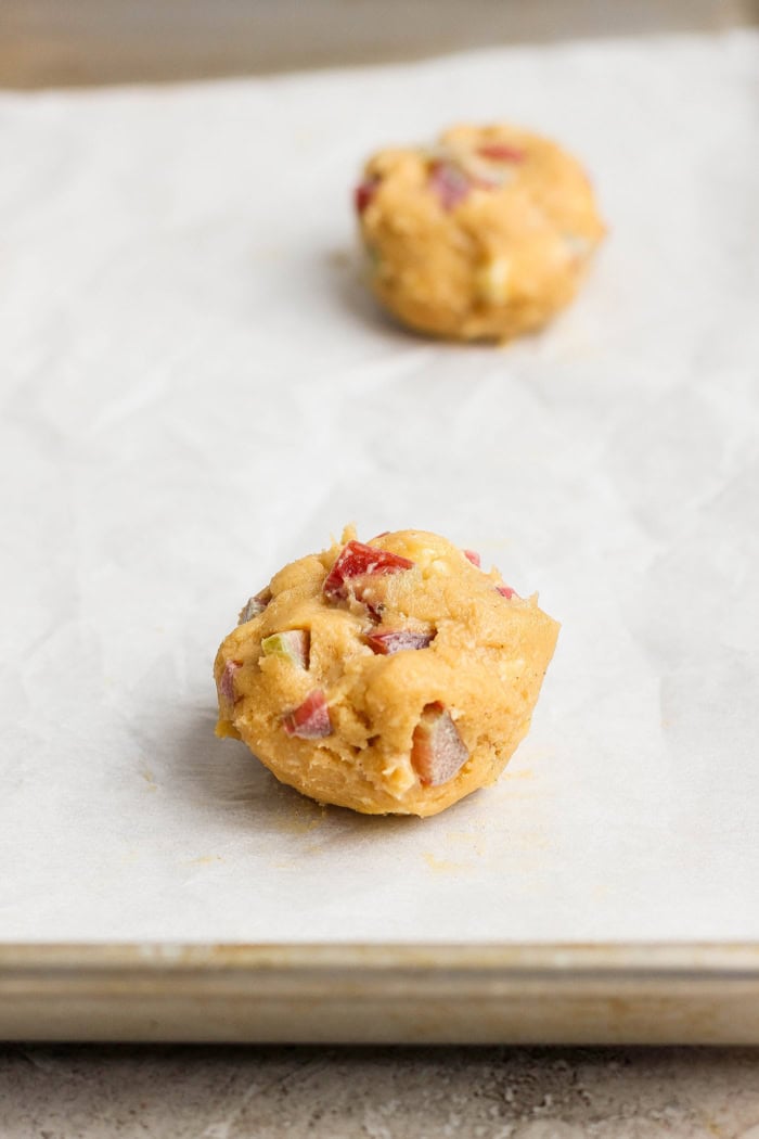 Balls of rhubarb cookie dough on parchment-lined baking sheet
