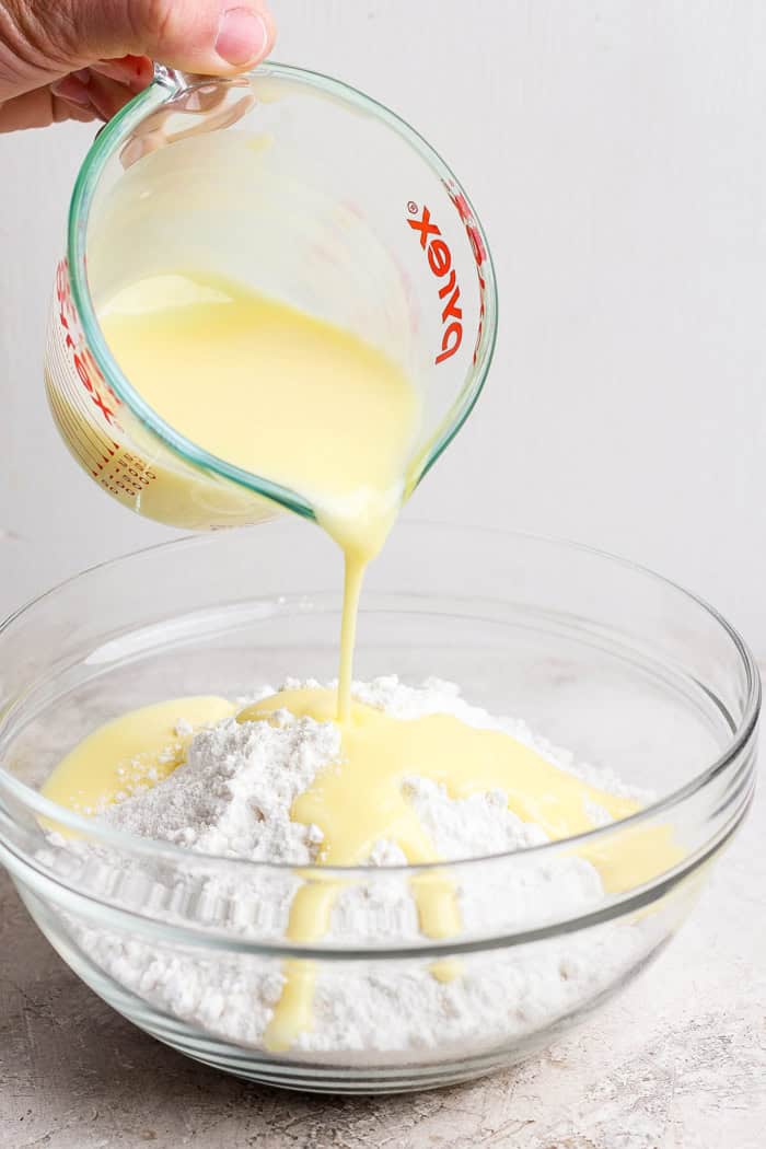 Pouring melted butter into bowl of cake mix