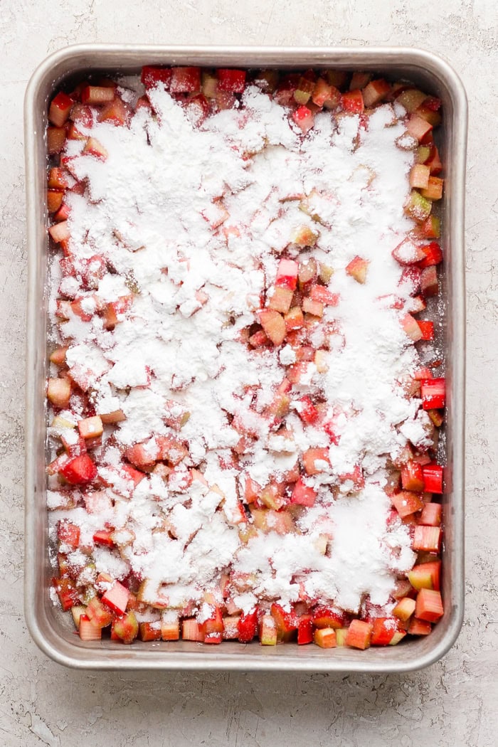 Overhead view of cornstarch added to rhubarb in baking pan