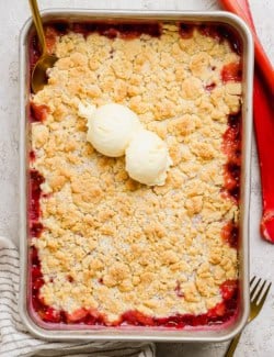 Overhead view of rhubarb dump cake in pan with vanilla ice cream on top