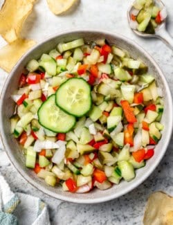 Overhead view of pickle de gallo in bowl with two cucumber slices for garnish