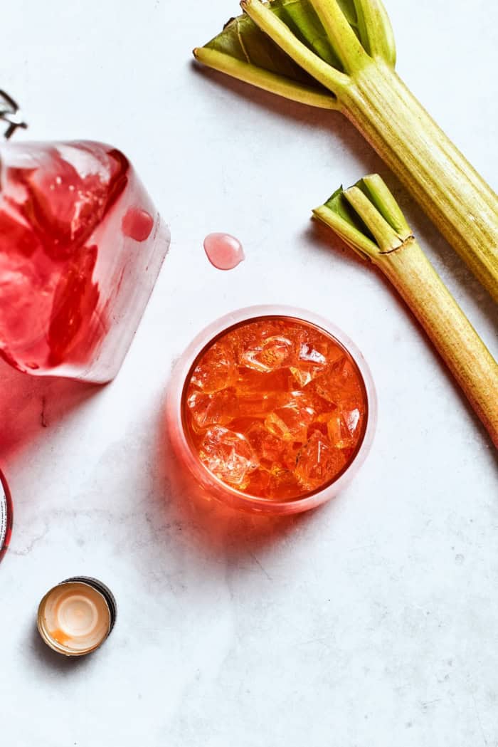 Overhead view of rhubarb spritz, rhubarb syrup, and fresh rhubarb