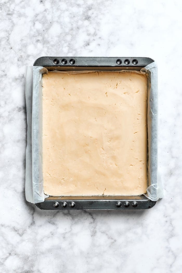 Buttery shortbread is layered with rhubarb custard to create these irresistible Rhubarb Custard Bars. Don't skip the cream cheese topping! Overhead view of crust for rhubarb custard bars