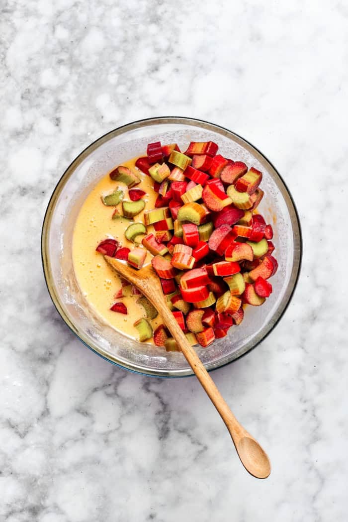 Buttery shortbread is layered with rhubarb custard to create these irresistible Rhubarb Custard Bars. Don't skip the cream cheese topping! Overhead view of rhubarb added to bowl of custard