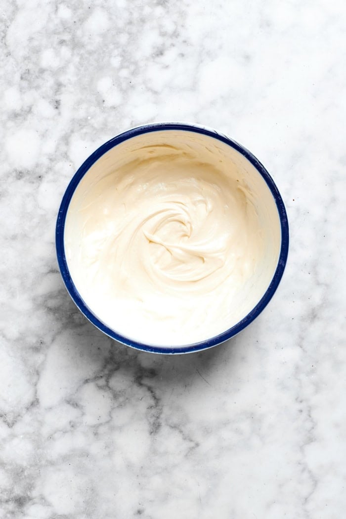 Buttery shortbread is layered with rhubarb custard to create these irresistible Rhubarb Custard Bars. Don't skip the cream cheese topping! Overhead view of whipped cream cheese topping in bowl