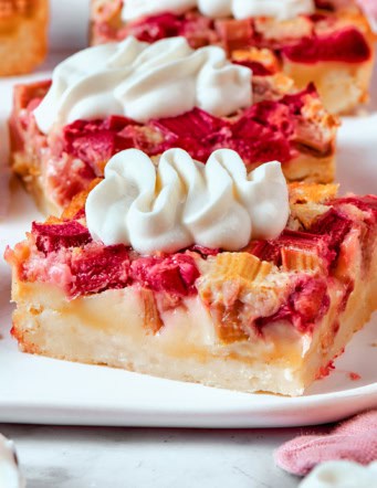 rhubarb custard bars with cream cheese topping, on a white platter