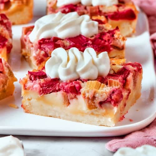 rhubarb custard bars with cream cheese topping, on a white platter