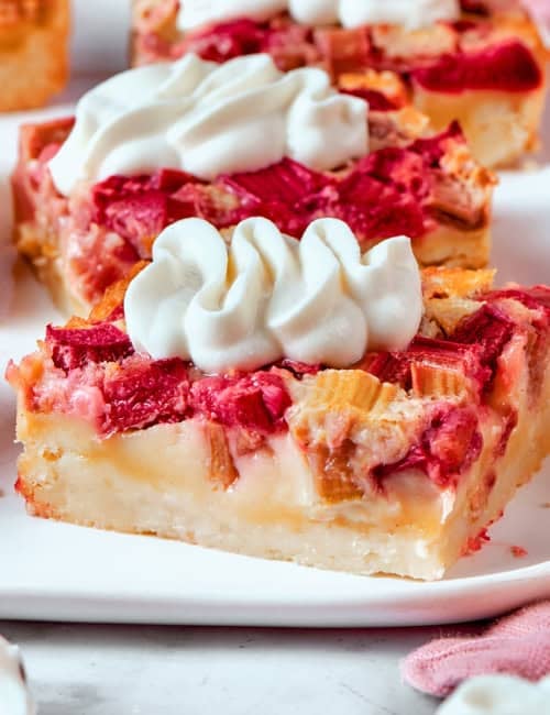rhubarb custard bars with cream cheese topping, on a white platter