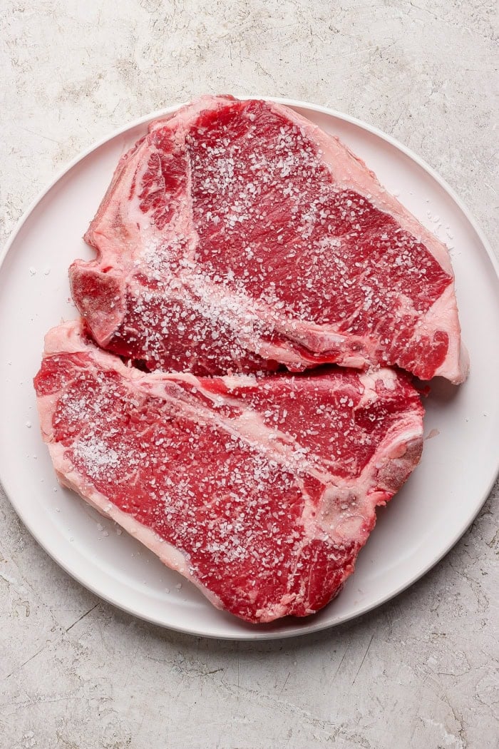 Overhead view of 2 t-bone steaks seasoned with salt