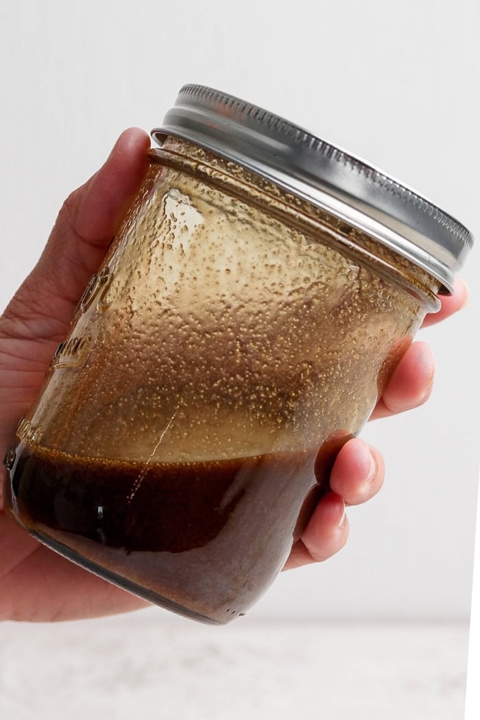 Hand holding jar of glaze for grilled steak