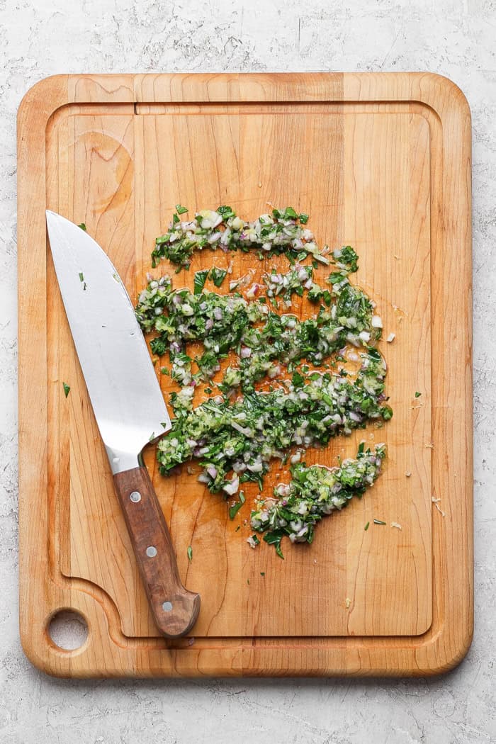 Overhead view of herbed board sauce on cutting board with knife