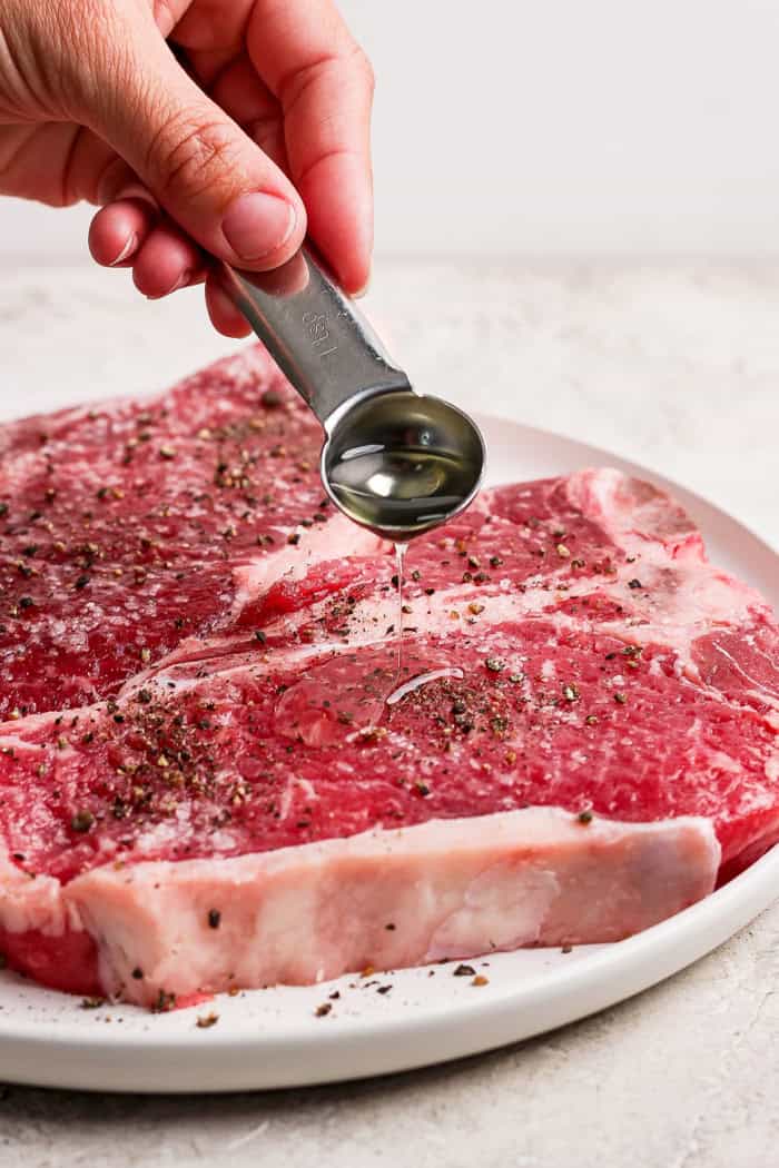 Drizzling olive oil onto t-bone steak