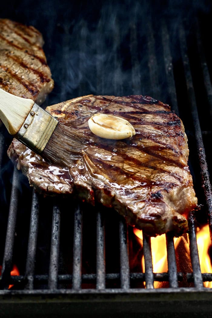Brushing glaze onto t-bone steak as it grills