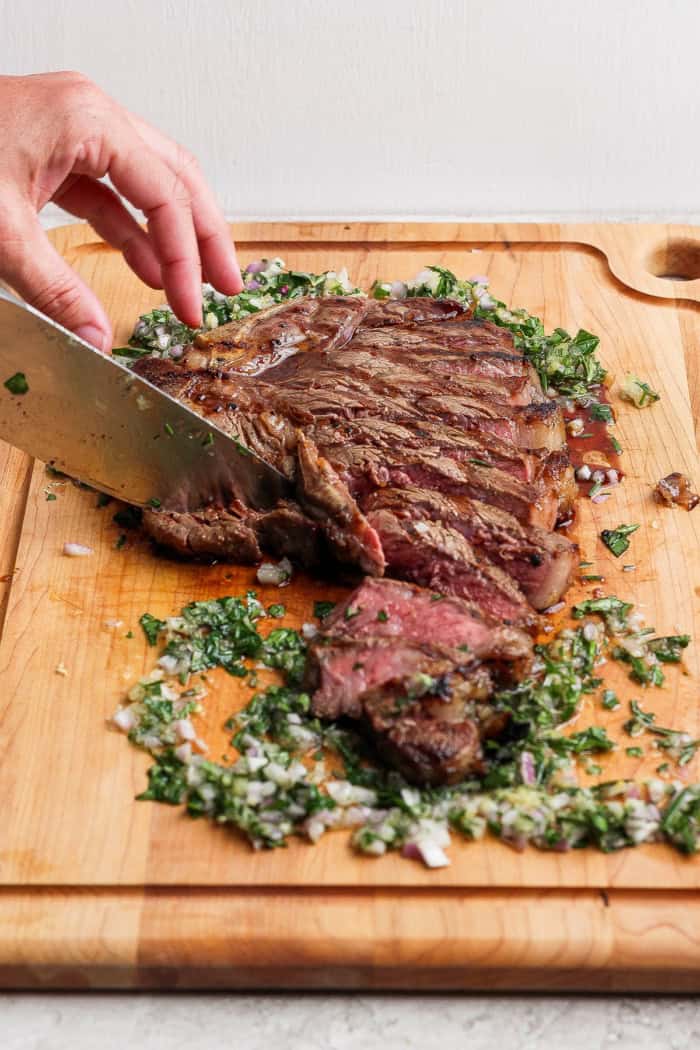 Slicing steak on cutting board with board sauce