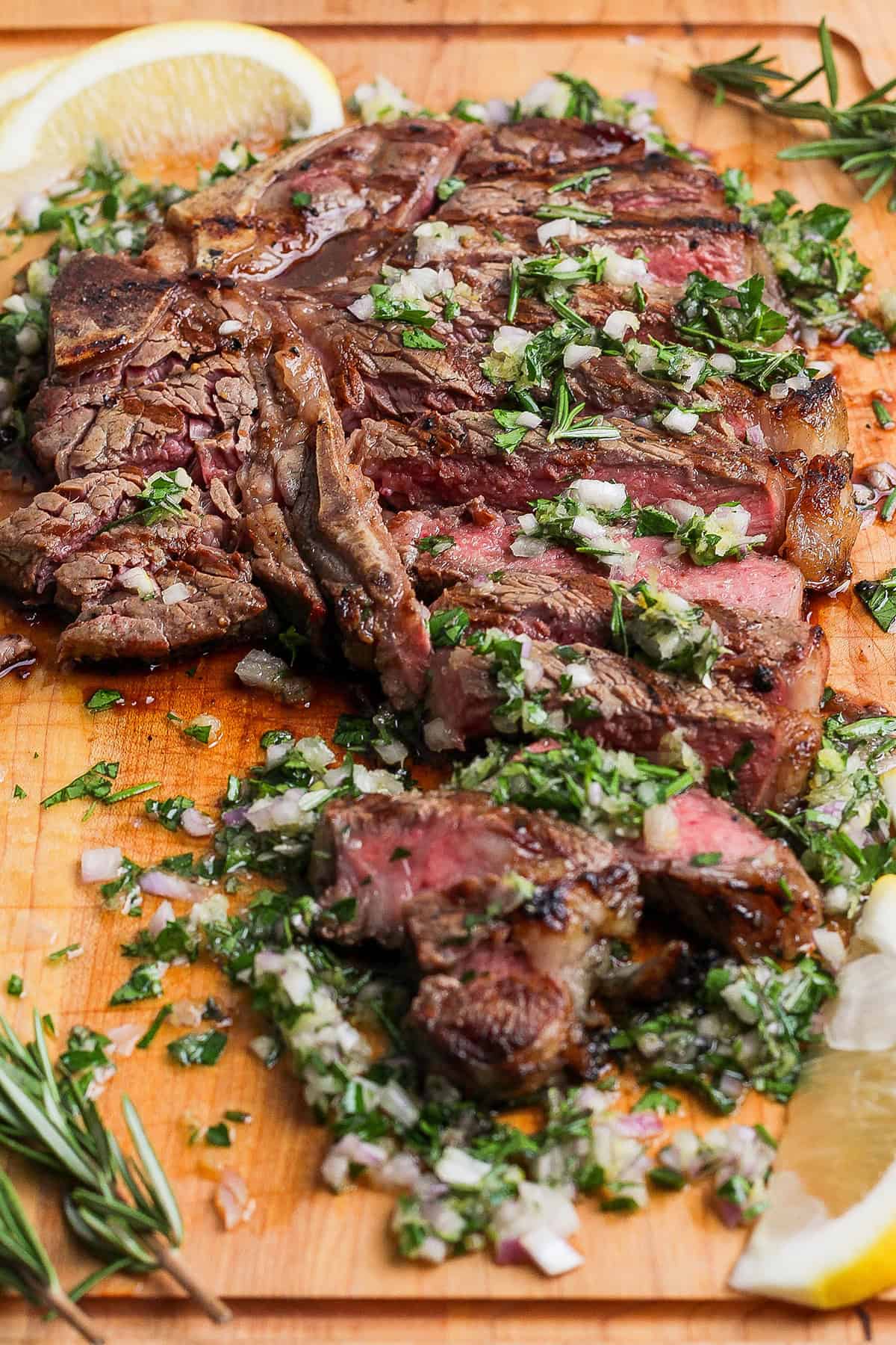 Grilled t-bone steak on cutting board with board sauce