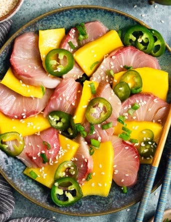 Overhead view of hamachi crudo on plate with mango and pickled jalapeno