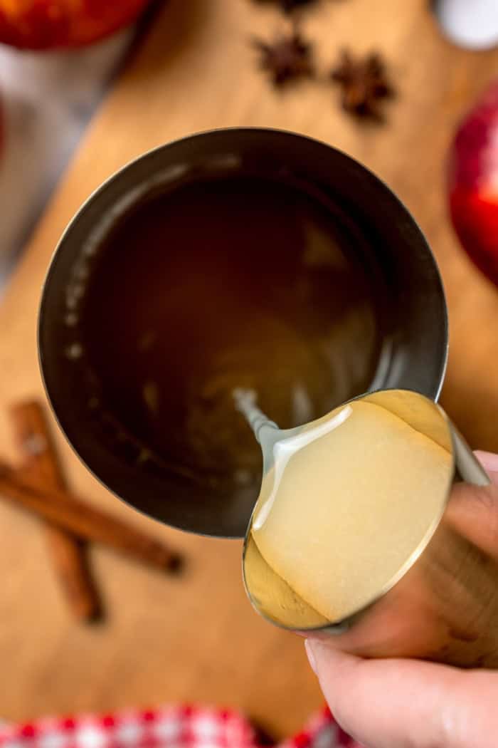 A fall spin on the classic, this Apple Cider Margarita is lightly sweetened with maple syrup and a cinnamon rim add a festive touch! Pouring tequila into cocktail shaker.