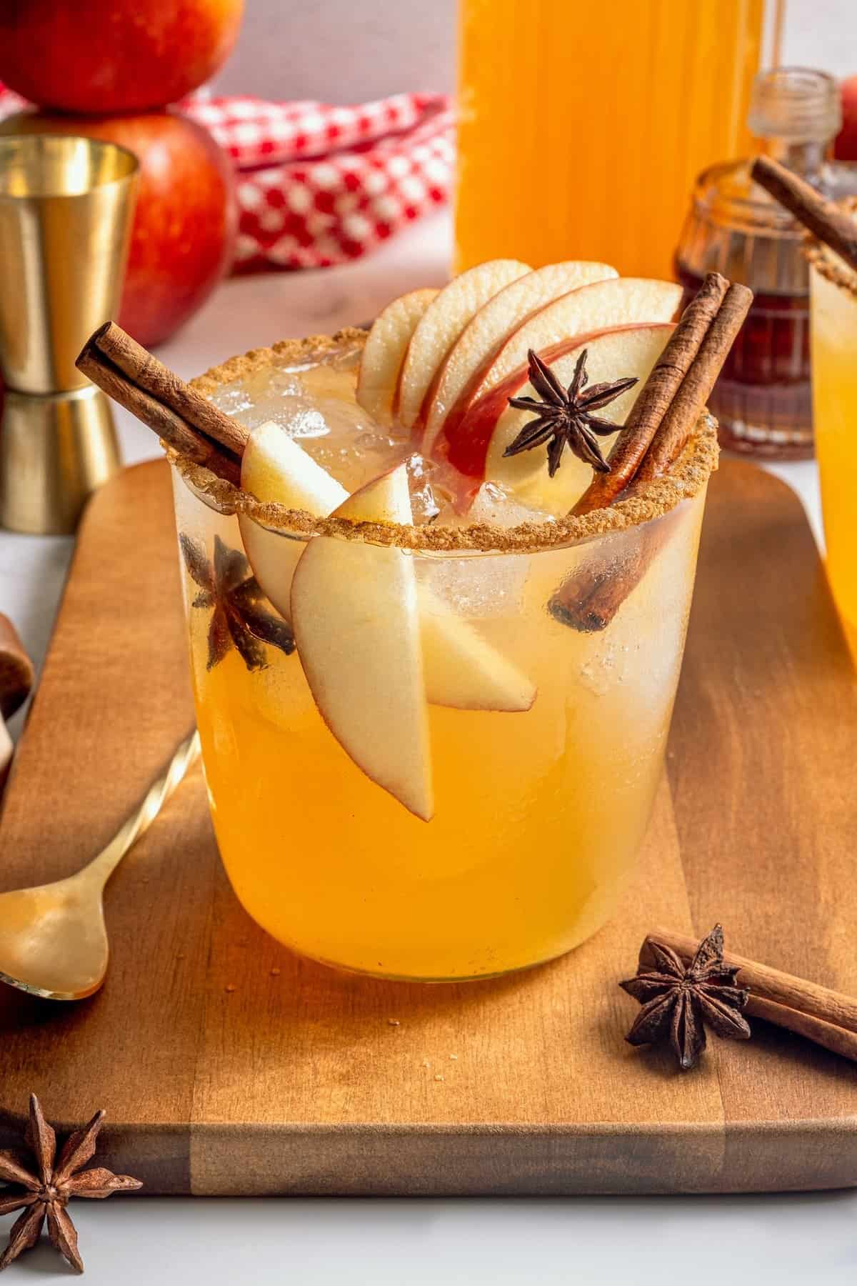 A fall spin on the classic, this Apple Cider Margarita is lightly sweetened with maple syrup and a cinnamon rim add a festive touch! Apple cider margarita in rimmed glass with apple slices, star anise, and cinnamon stick.
