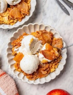 Overhead view of apple dump cake on 2 plates with vanilla ice cream.