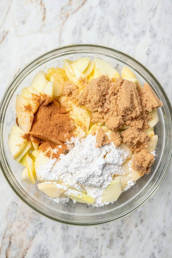 A brown sugar oat crumble mixture doubles as a crust and a topping for these easy Apple Pie Bars. The perfect fall treat for a crowd! Ingredients for apple filling in glass bowl.