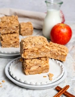 Stack of 2 apple pie bars on 2 plates.