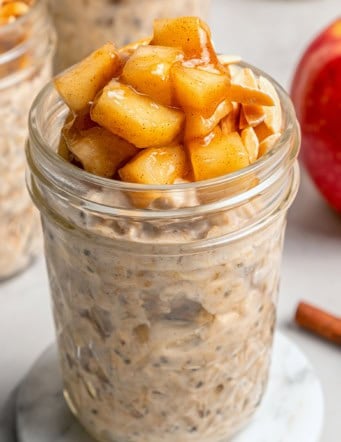 a jar of apple overnight oats with sauteed apples and slivered almonds on top