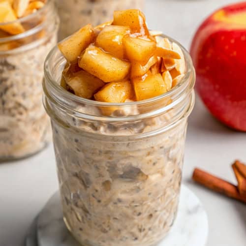 a jar of apple overnight oats with sauteed apples and slivered almonds on top