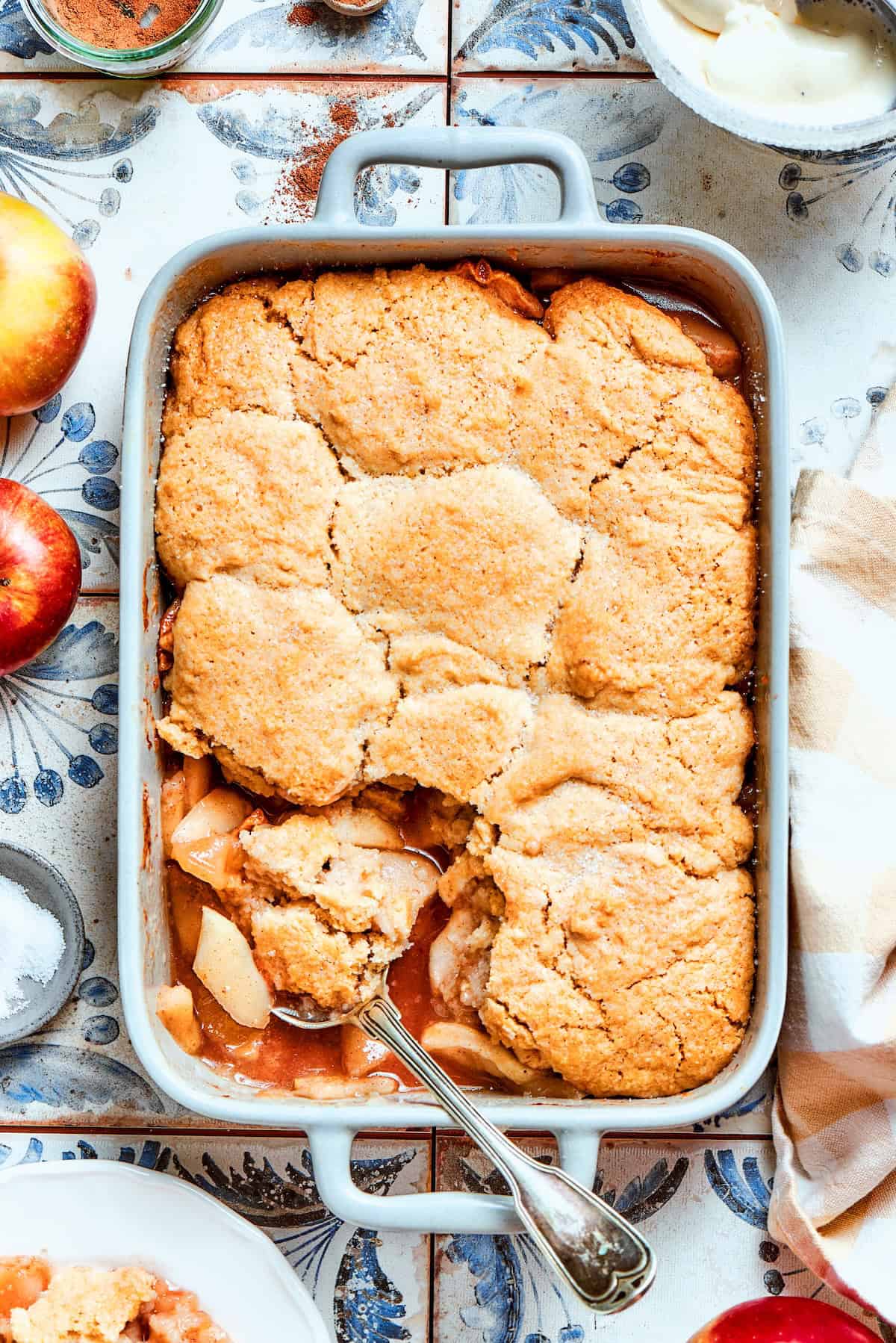 Apple Cobbler has apple pie flavor in an easier form, swapping the crust for a biscuit-like topping that bakes up tender and golden brown! a white rectangular baking dish with baked Apple Cobbler