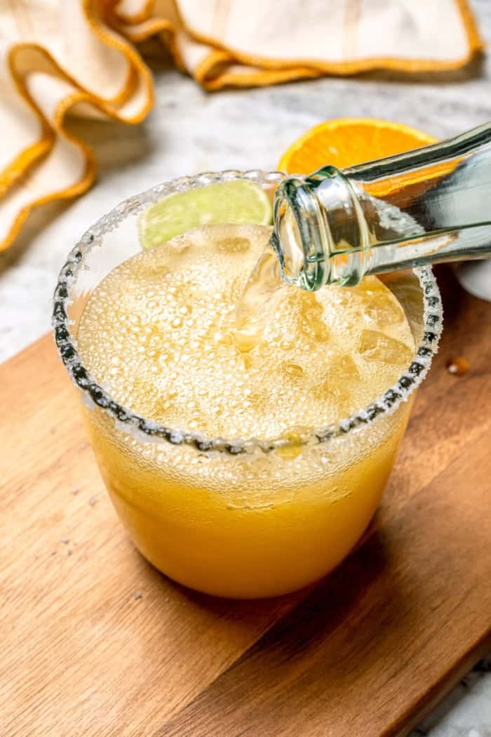 Deliciously tart and refreshing, this fizzy Margarita Mocktail has the bright citrus flavor of the real-deal, in non-alcoholic form! Pouring sparkling water into glass for margarita mocktail
