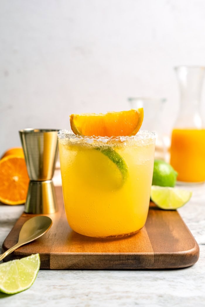 Deliciously tart and refreshing, this fizzy Margarita Mocktail has the bright citrus flavor of the real-deal, in non-alcoholic form! Margarita mocktail on wood board with spoon and jigger
