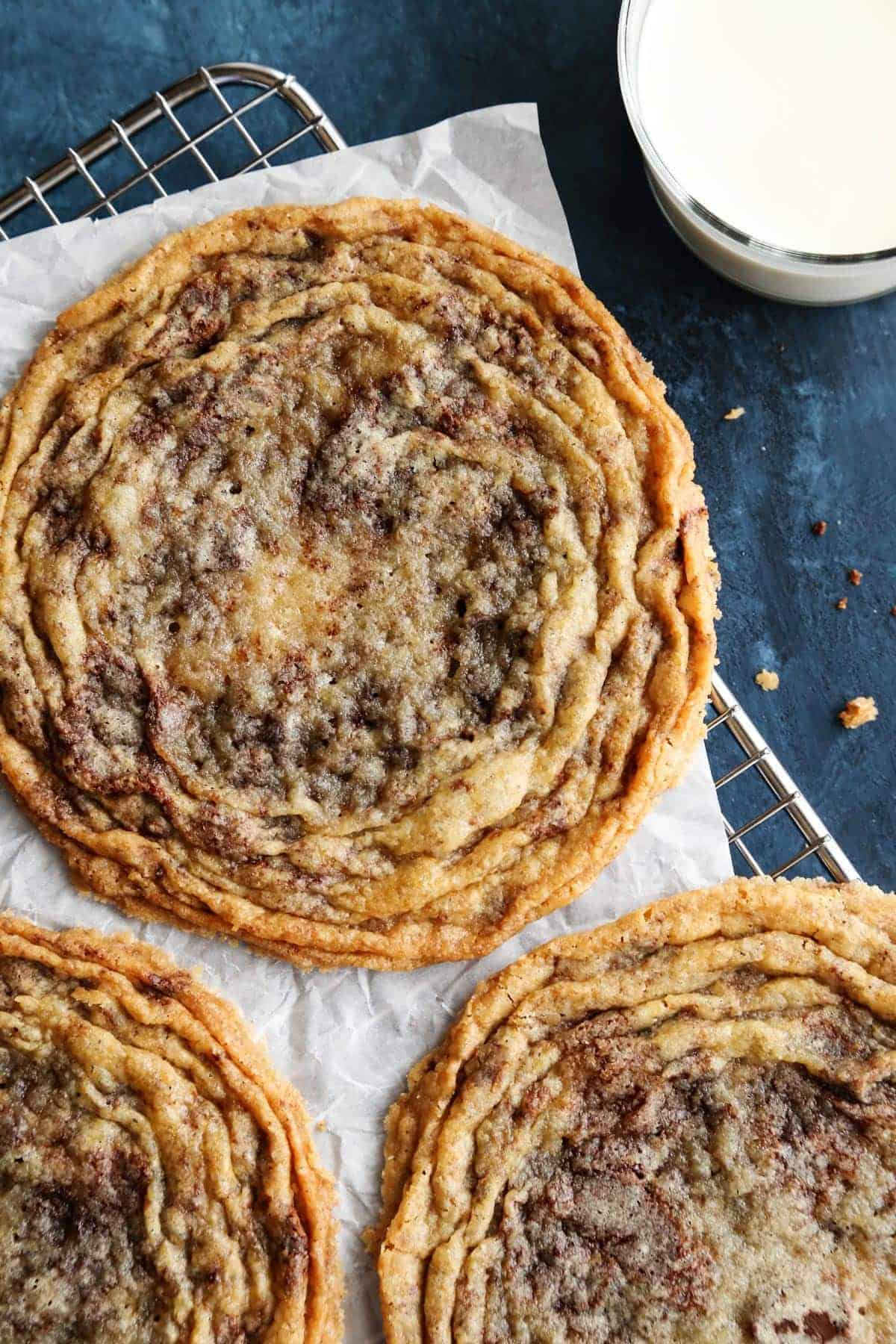 overhead photo of 3 giant pan-banging chocolate chip cookies on a cooling rack