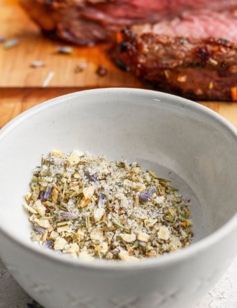 Steak seasoning in small bowl with steak in background.