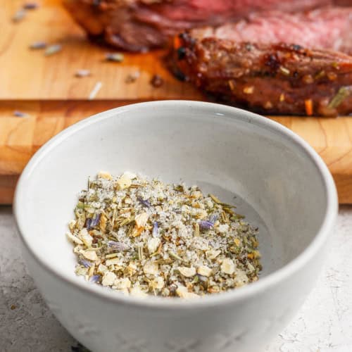 Steak seasoning in small bowl with steak in background.
