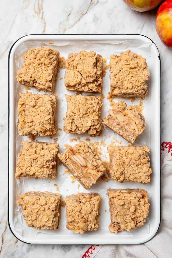 A brown sugar oat crumble mixture doubles as a crust and a topping for these easy Apple Pie Bars. The perfect fall treat for a crowd! baked and sliced apple pie bars in a white rectangular pan