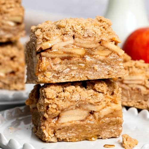 two apple pie bars stacked on top of each other, on a white plate