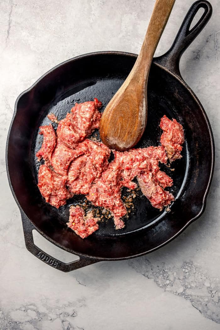 Pork sausage cooking in cast iron skillet.
