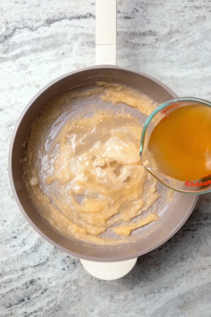Pouring broth into roux for ham gravy.